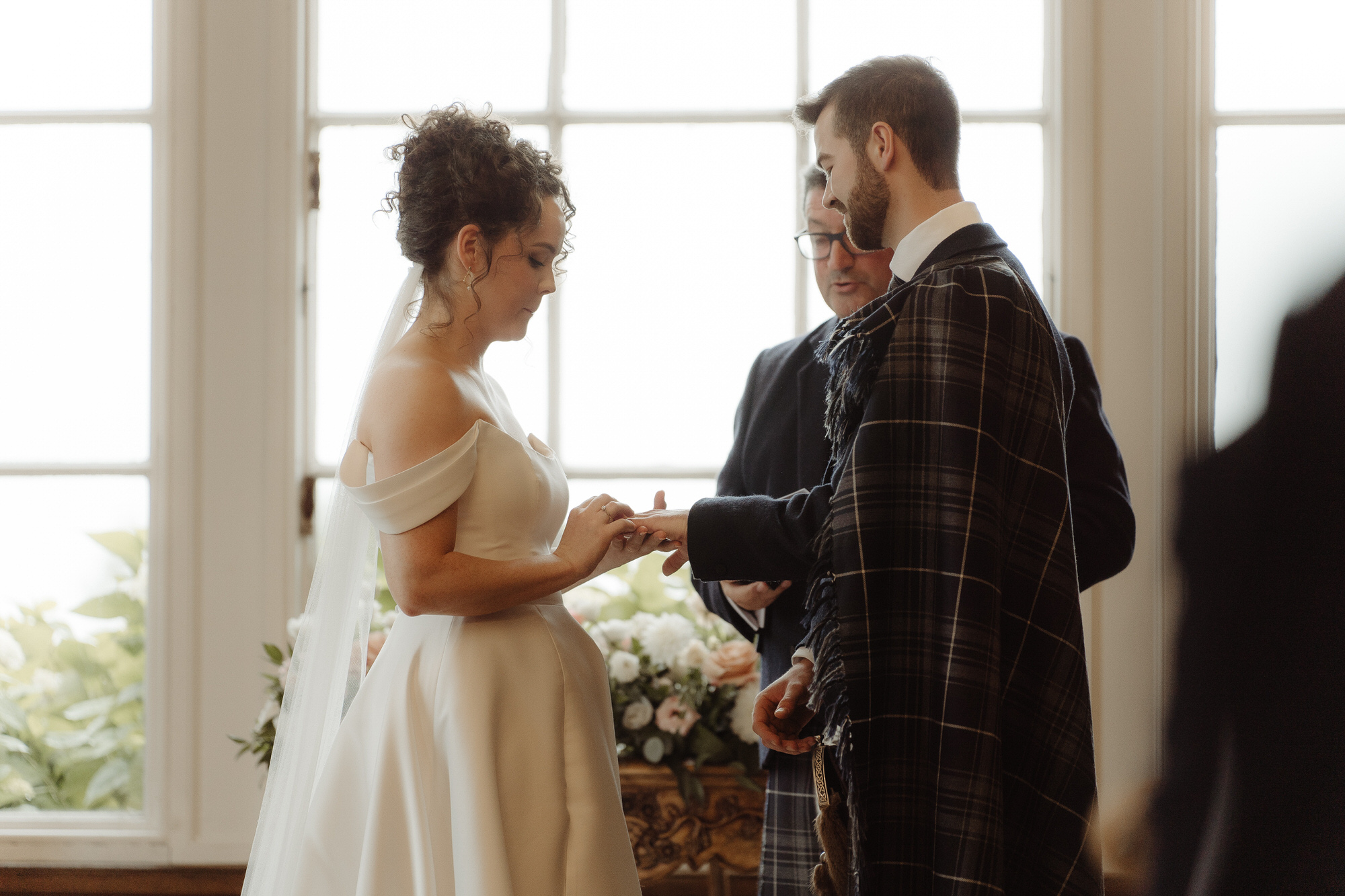 Bride puts a ring on the grooms finger at Kinmount House wedding