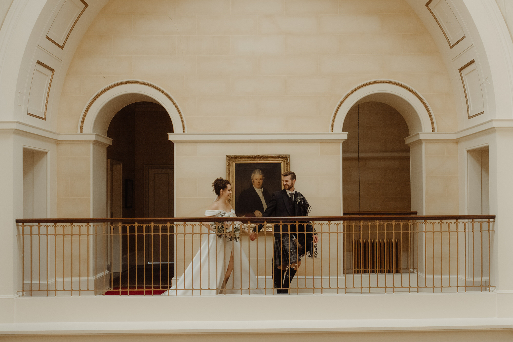 Bride and groom walk along the upper gallery at Kinmount House wedding