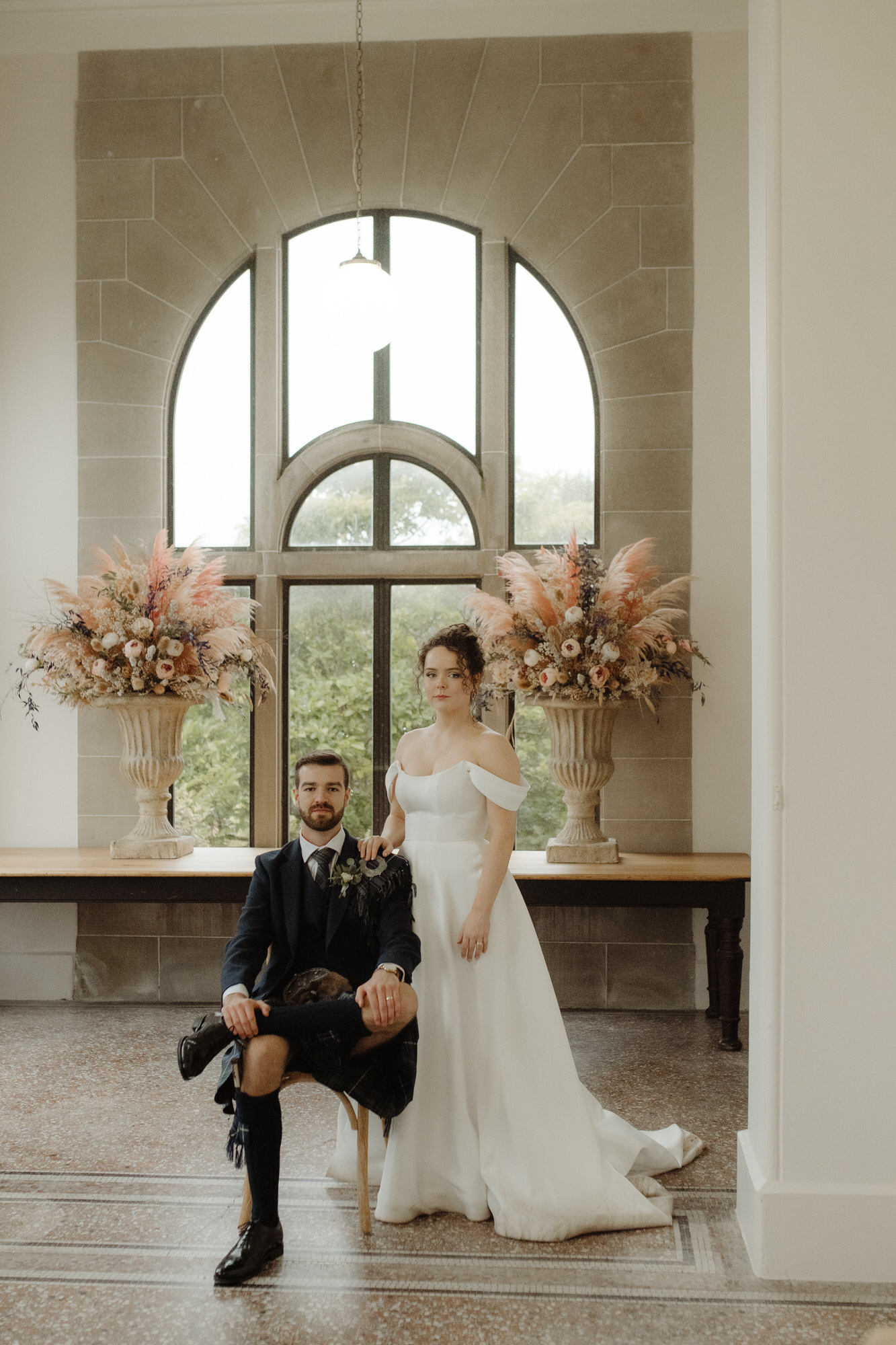 Bride and groom make a royal pose in the orangery at Kinmount House wedding