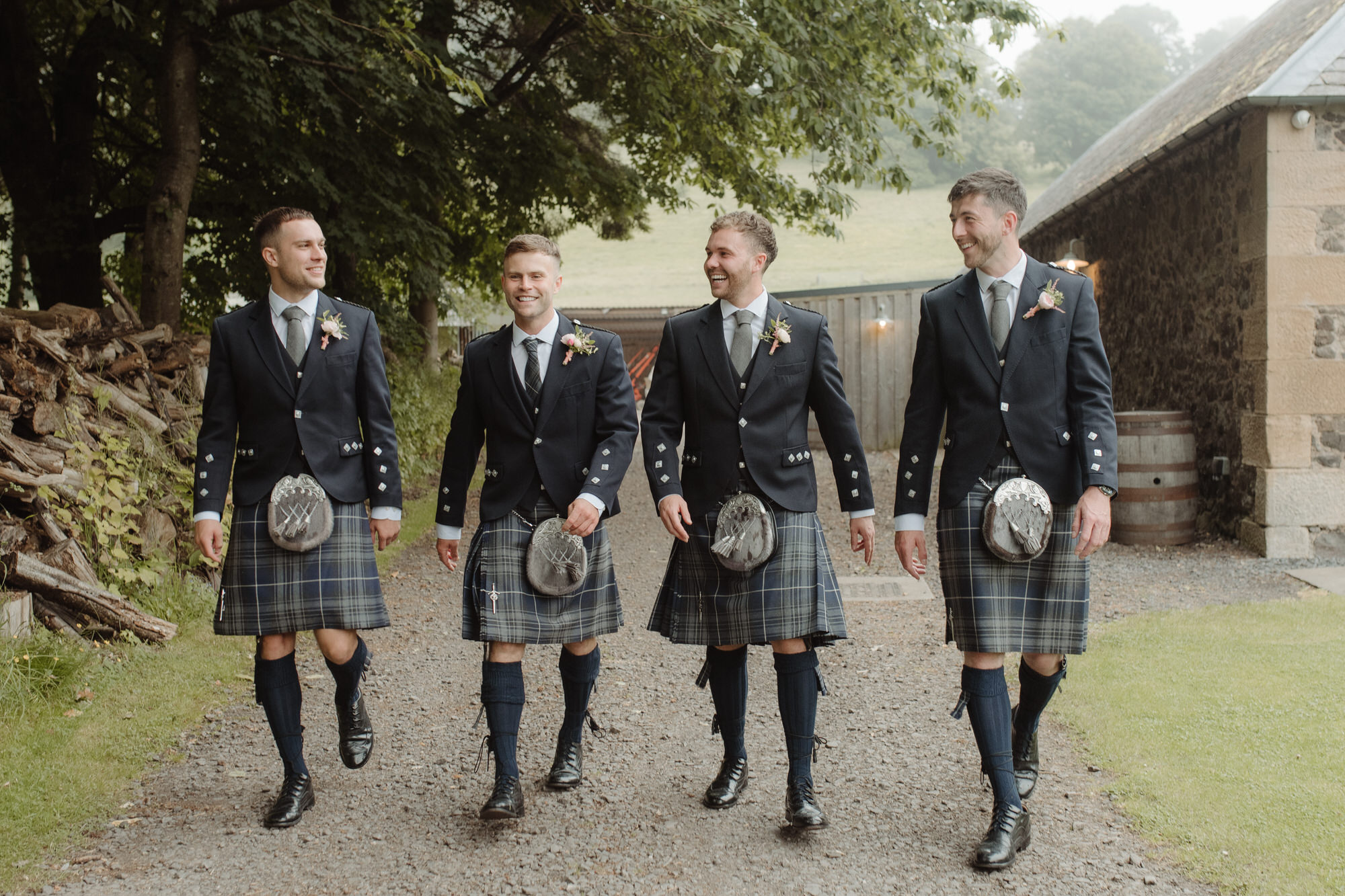 Groomsmen walk beside byre at the Byre at Inchyra.