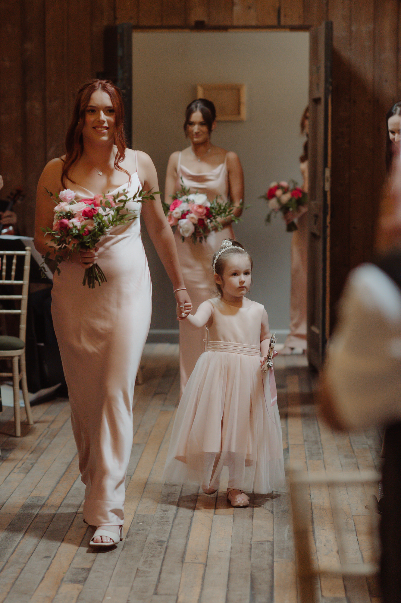 Bridesmaid and flower girl walk down the aisle holding hands at the Byre at Inchyra.