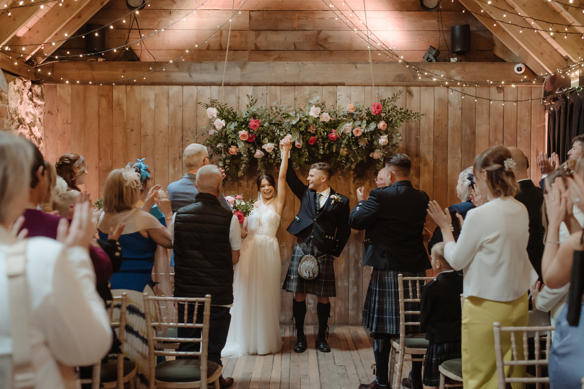 Newly married couple and raise their hands at their wedding ceremony at the Byre at Inchyra.