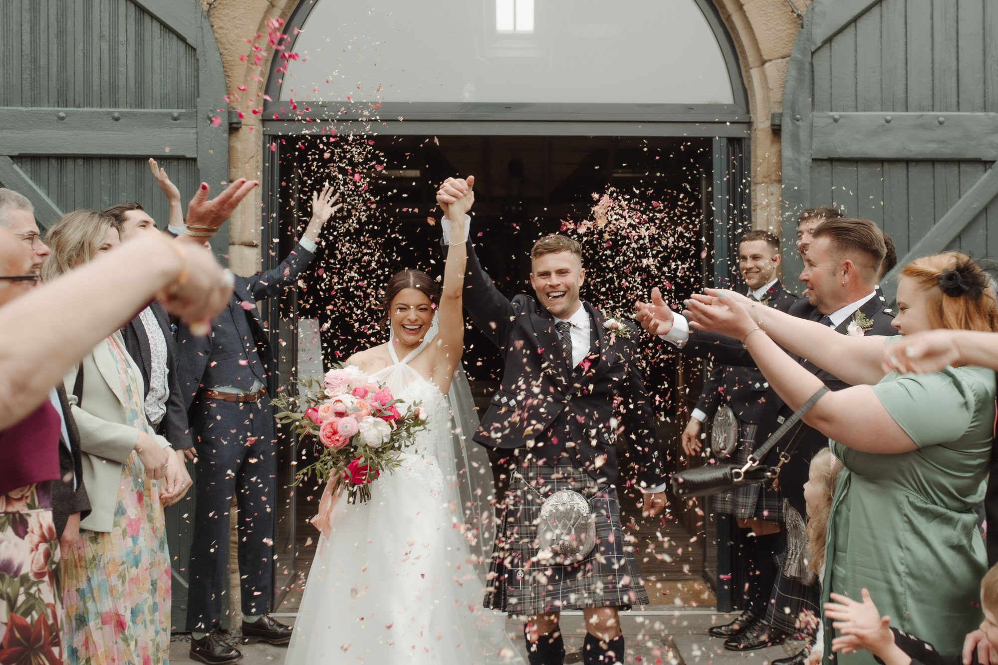 Newly married couple cheer under confetti at the Byre at Inchyra.