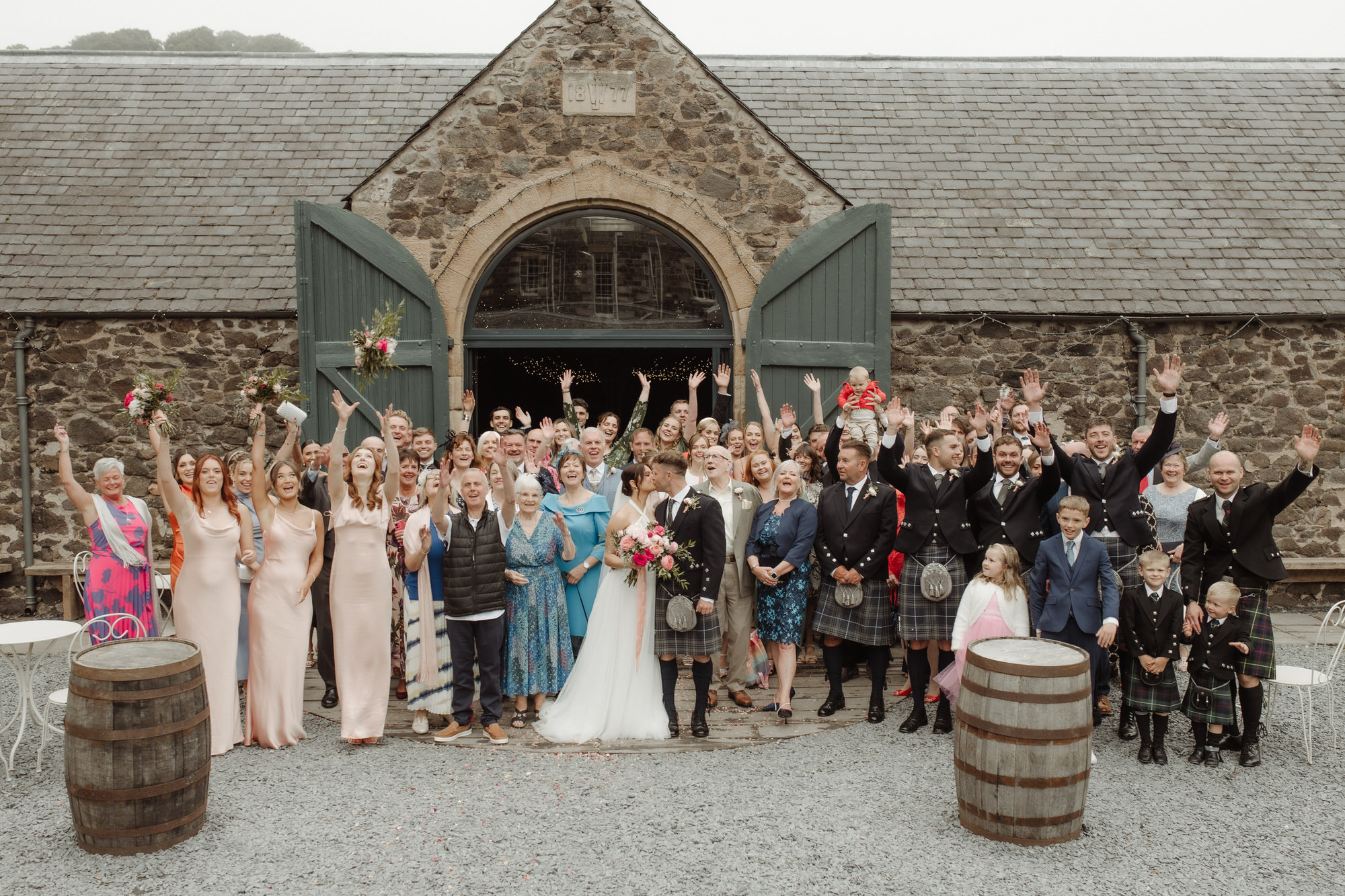 Large happy wedding group photo in front of the Byre at Inchyra.