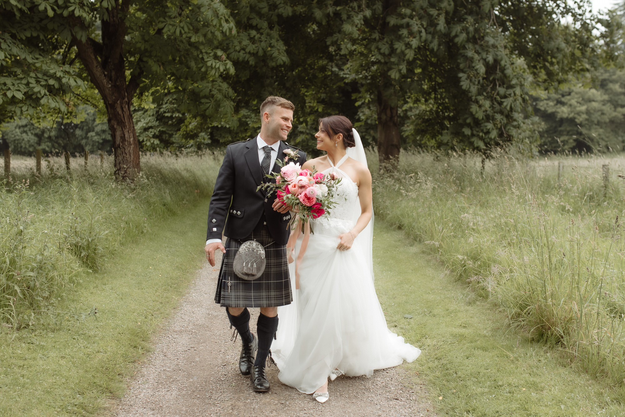 Bride and Groom walk side by side on a gravel track at the Byre at Inchyra