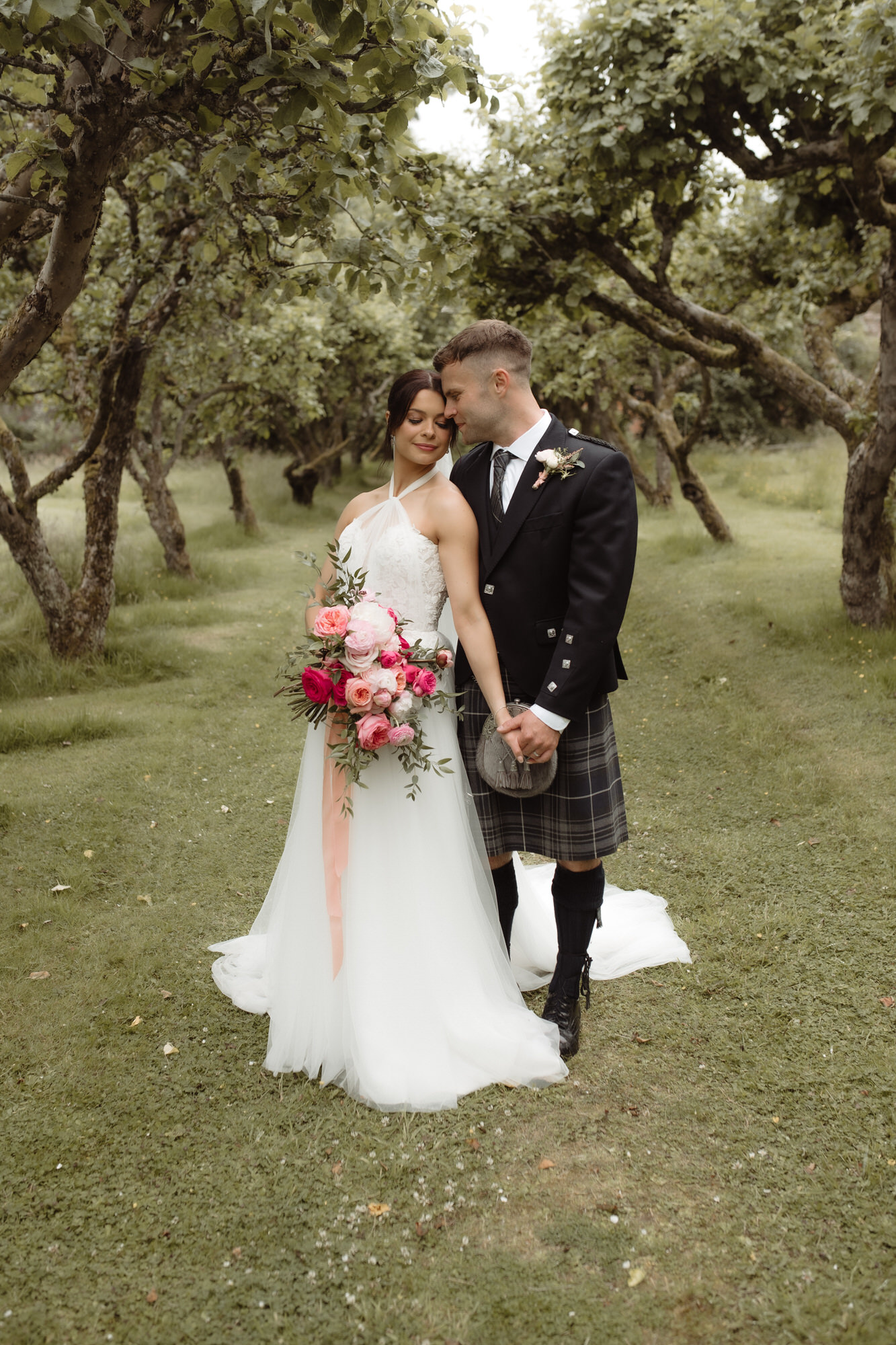 Couple cuddle in the orchard at the Byre at Inchyra.