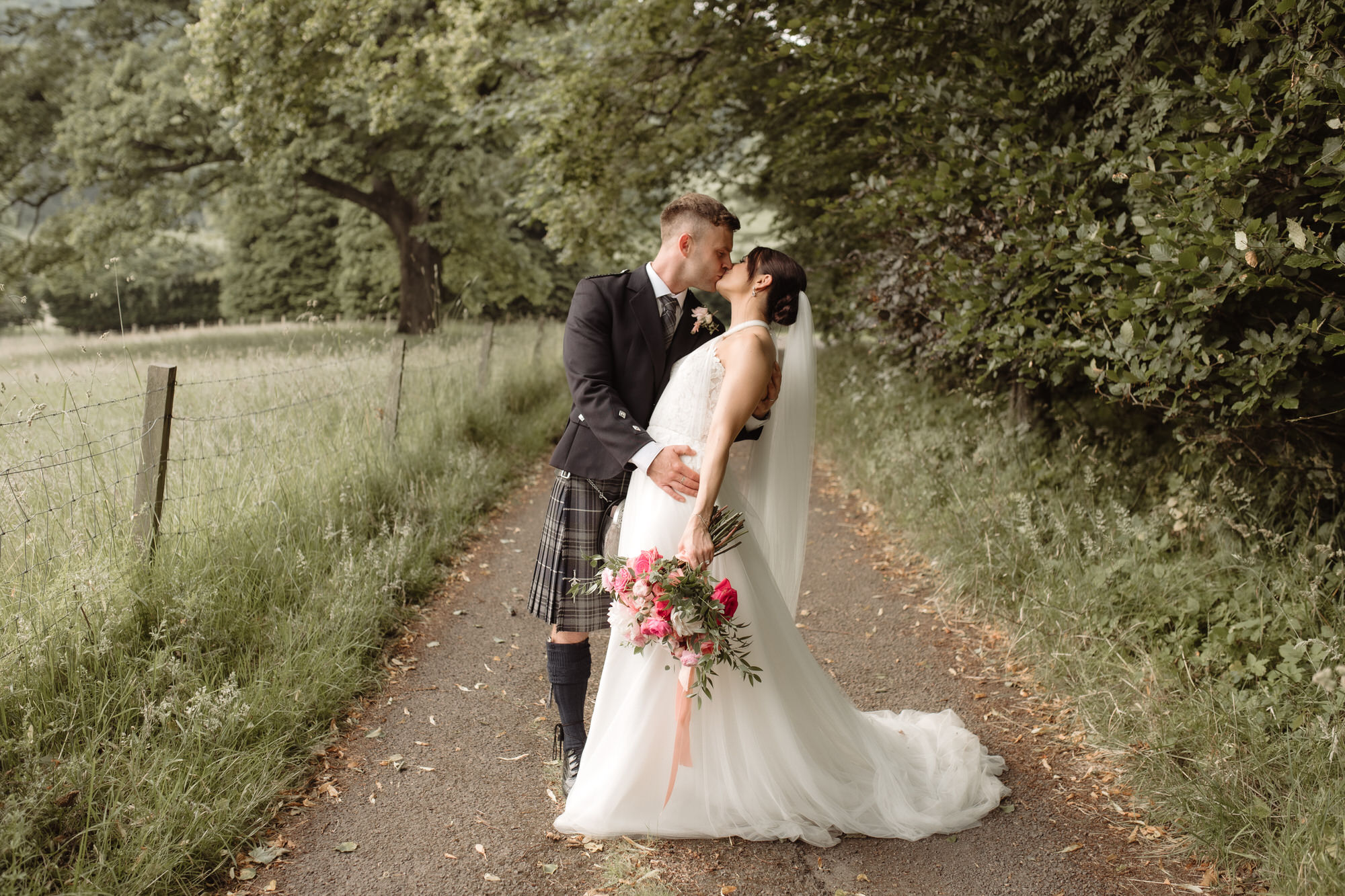 Bride and Groom kiss on a country track at the Byre at Inchyra.