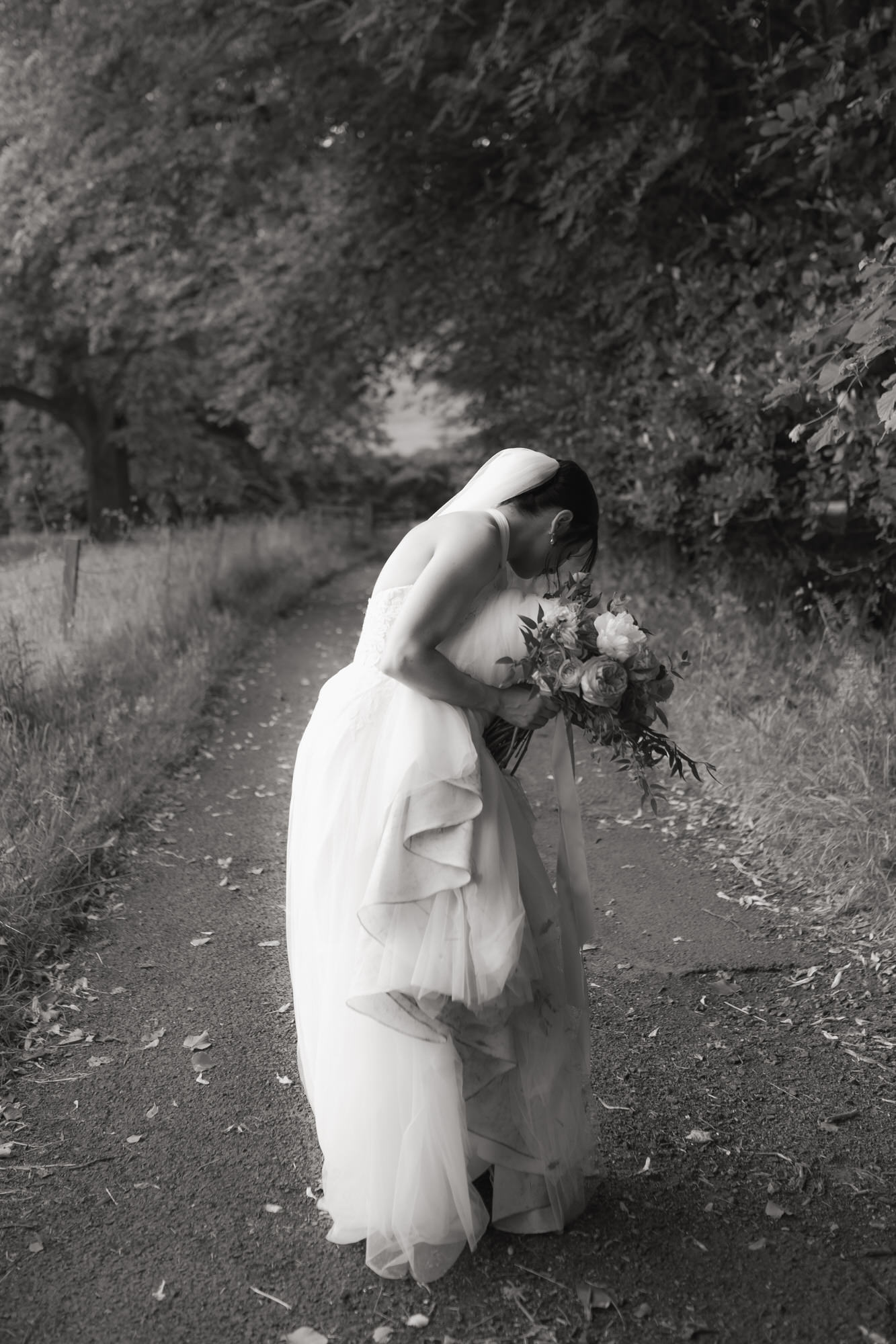 Black and white portrait of bride lifting her wedding dress train at the Byre at Inchyra.