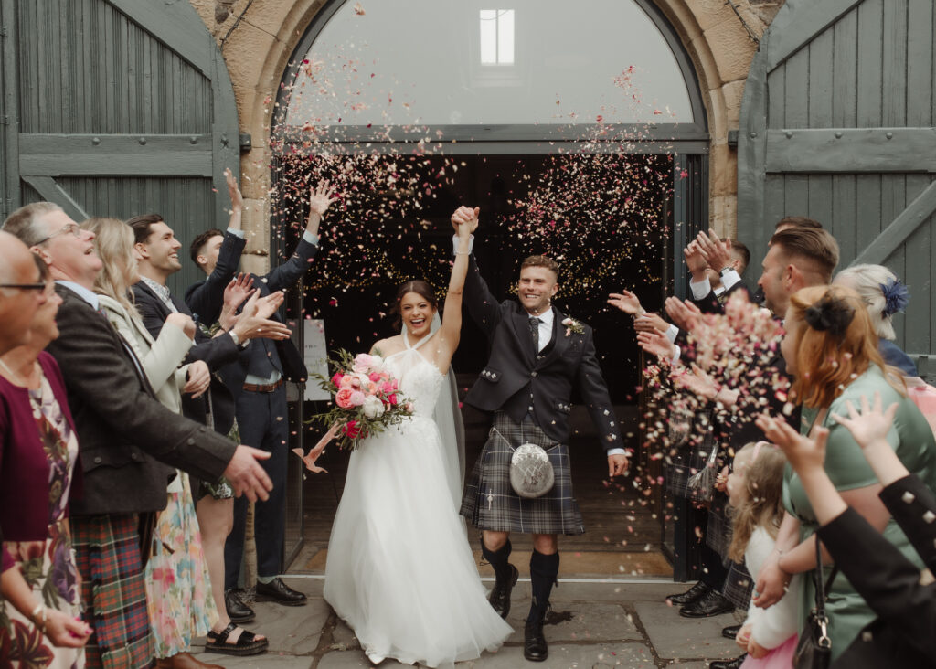 Bride and Groom throw confetti at The Byre at Inchyra wedding venue.