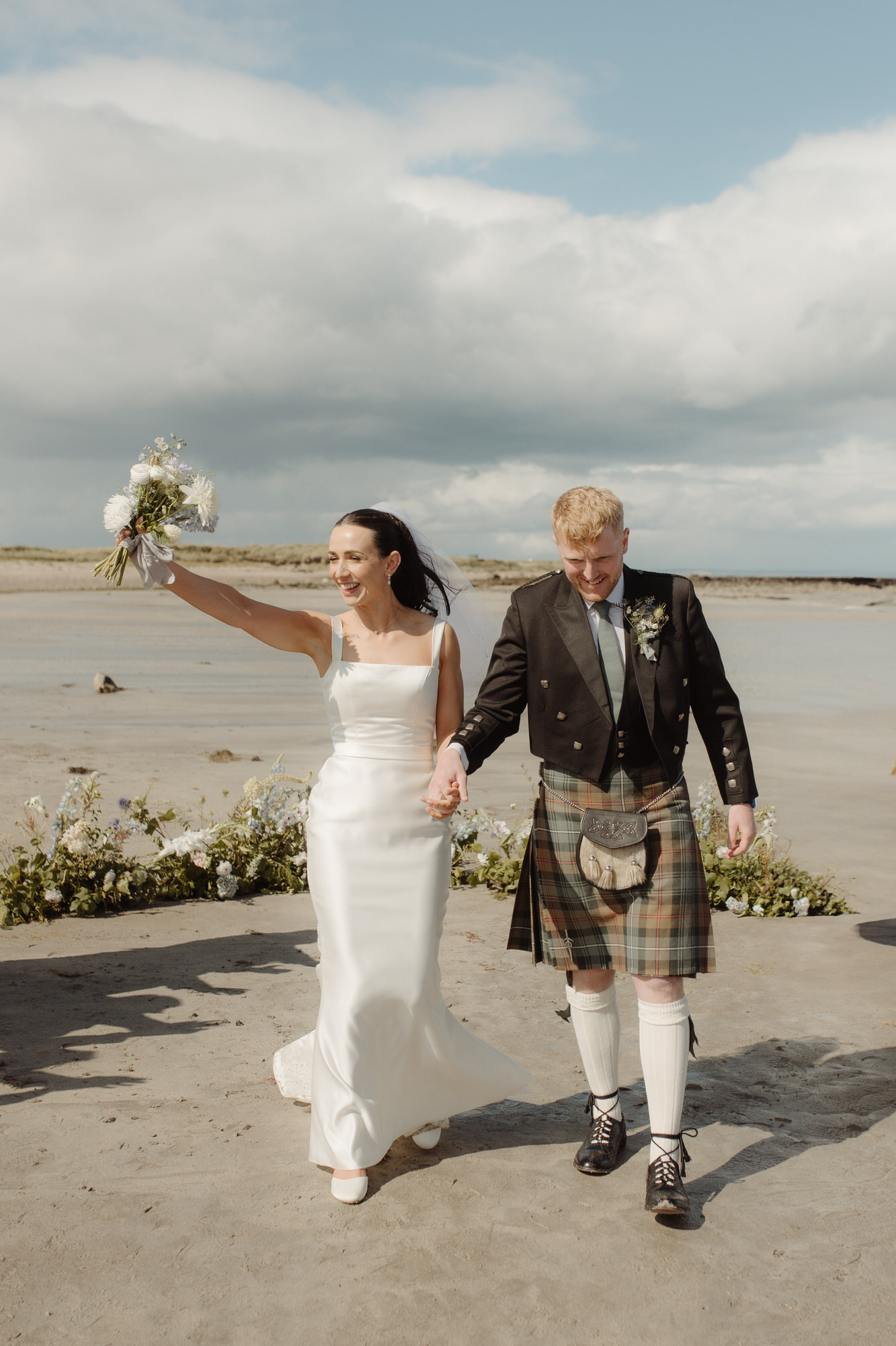 Bride and Groom cheer at Scottish beach wedding.