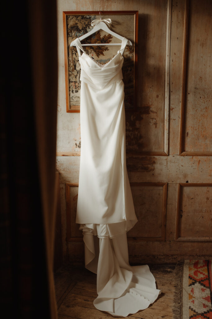 Wedding dress hangs by the window at Neidpath Castle. Wedding & Elopement Photographer in Scotland.