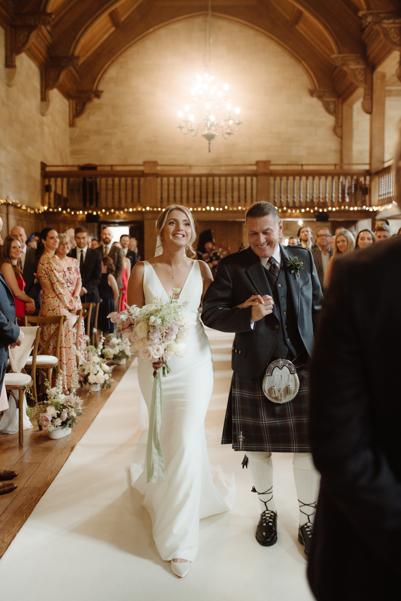 Bride smiles with her father at the top of the aisle during wedding ceremony at Achnagairn Castle.