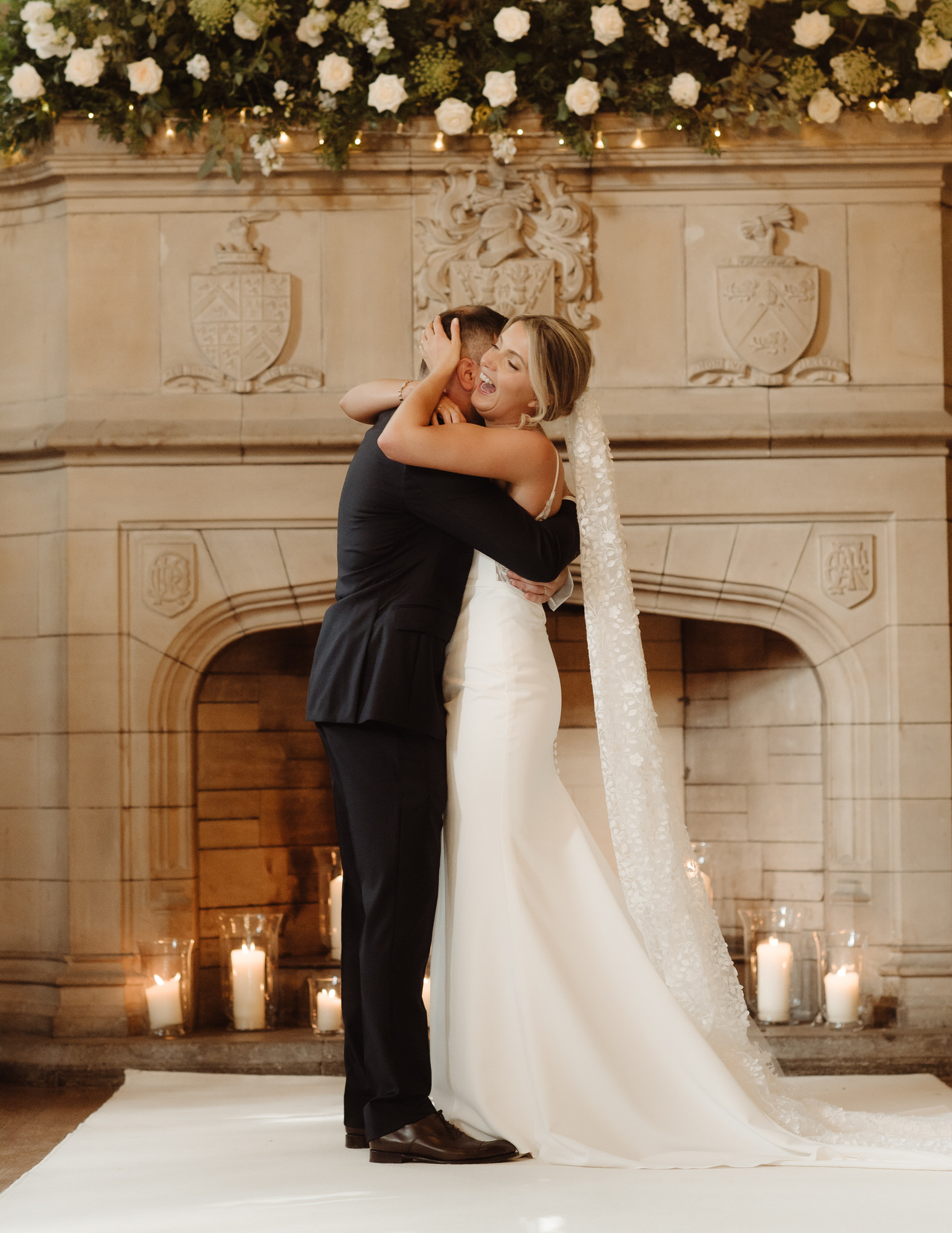 Bride and Groom cuddle in front of grand fireplace at Achnagairn Castle.