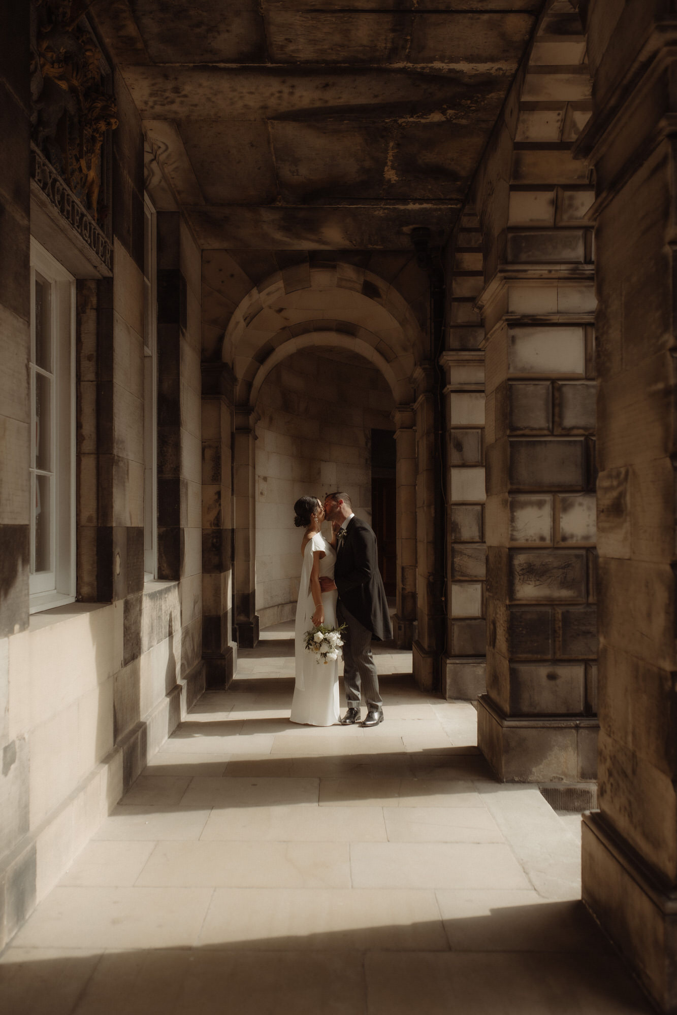 Couple kiss in the Edinburgh cloisters.