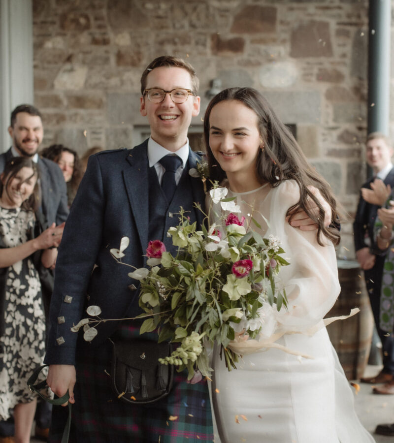 Man and woman walk through a confetti toss at their wedding.