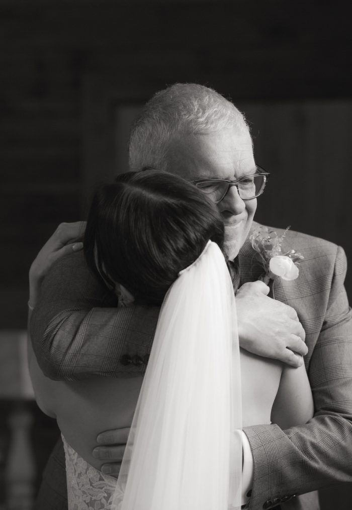 Father hugs bride.